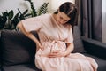 Pregnant lady having backache at home. Unhappy woman suffering from lower back pain sitting on sofa in living room. Tired pregnant Royalty Free Stock Photo