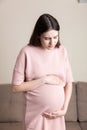 Pregnant Lady Having Massaging Lower belly Sitting On Sofa Indoor. Pregnancy Problems Concept. Maternity healthcare Royalty Free Stock Photo