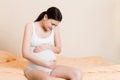 Pregnant Lady Having Massaging Lower belly Sitting On Sofa Indoor. Pregnancy Problems Concept. Maternity healthcare Royalty Free Stock Photo