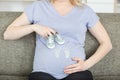 pregnant lady holding lottle boots next to bump