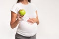 Pregnant Lady Showing Apple Touching Belly, White Background, Cropped