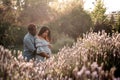 Pregnant Latina woman and African couple embracing in a lush green sunlit park