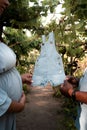 Pregnant Latina woman and African couple holding a small baby dungaree in a lush green park