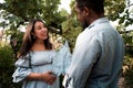 Pregnant Latina woman and African couple holding a small baby dungaree in a lush green park