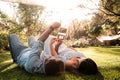 Pregnant Latina woman and African couple laying in a green and sunlit park looking at baby sonogram