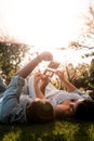 Pregnant Latina woman and African couple laying in a green and sunlit park looking at baby sonogram