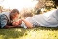 Pregnant Latina woman and African couple laying in a lush green and bright sunlit park