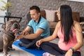 A pregnant man and woman couple practice yoga at home and play with their brown bulldog Royalty Free Stock Photo