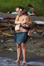 A pregnant mom hugging her grown child on the black beach