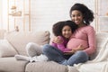 Happy expecting afro woman hugging with her little daughter at home Royalty Free Stock Photo