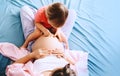 Pregnant mother with her little daughter relaxing in bed. Second pregnancy. Maternity and parenting concept Royalty Free Stock Photo