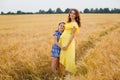 Pregnant mother and daughter in a wheat field at sunset. Gentle family hugs of mother and child in nature Royalty Free Stock Photo