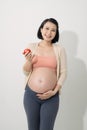 Pregnant mother eats apple happily and smiling