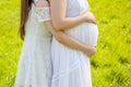 Pregnant mother with her daughter white dress in the green park sunny day