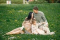 Pregnant mother and her little daughter and husband sitting on a grass in a park Royalty Free Stock Photo