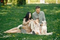 Pregnant mother and her little daughter and husband sitting on a grass in a park Royalty Free Stock Photo