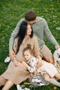 Pregnant mother and her little daughter and husband sitting on a grass in a park Royalty Free Stock Photo