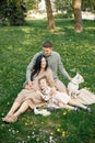 Pregnant mother and her little daughter and husband sitting on a grass in a park Royalty Free Stock Photo