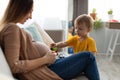 Pregnant mother and her toddler son spending time together at home, little boy touching gently mother pregnant tummy Royalty Free Stock Photo