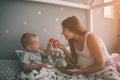 Pregnant mother and little boy son are eating an apple and peach in the bed t home in the morning. Casual lifestyle in Royalty Free Stock Photo