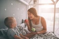 Pregnant mother and little boy son are eating an apple and peach in the bed t home in the morning. Casual lifestyle in Royalty Free Stock Photo