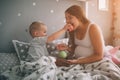 Pregnant mother and little boy son are eating an apple and peach in the bed t home in the morning. Casual lifestyle in Royalty Free Stock Photo