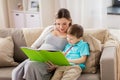 Pregnant mother and little son with book at home Royalty Free Stock Photo