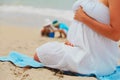 Pregnant mother relax on beach while kids play with sand Royalty Free Stock Photo