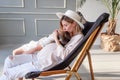 A pregnant mother sits on a wooden deck chair, hugs, kisses her older daughter Royalty Free Stock Photo