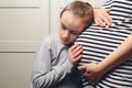 Pregnant mother and son at home. Cute boy with mom spending time together at home. Child boy hugging his mother pregnant tummy Royalty Free Stock Photo