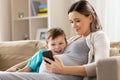 Pregnant mother and son with smartphone at home Royalty Free Stock Photo