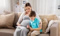Pregnant mother and son with workbook at home
