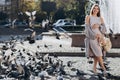 Pregnant mother stands near the pigeons in a sunny summer park. Walking on the street