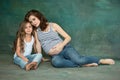 Pregnant mother with teen daughter. Family studio portrait over blue background Royalty Free Stock Photo