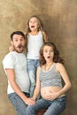 Pregnant mother with teen daughter and husband. Family studio portrait over brown background Royalty Free Stock Photo