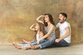 Pregnant mother with teen daughter and husband. Family studio portrait over brown background Royalty Free Stock Photo