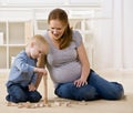 Pregnant mother watches son stack wooden blocks