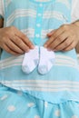 Pregnant mothers holding a small pair of socks on stomach.