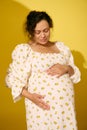 Pregnant pretty woman in sundress, gently caresses her belly, experiencing happy moments of her carefree happy pregnancy Royalty Free Stock Photo