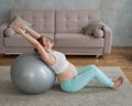 Pregnant red-haired woman doing exercises on fitness ball at home. Royalty Free Stock Photo
