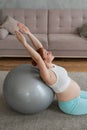 Pregnant red-haired woman doing exercises on fitness ball at home. Royalty Free Stock Photo