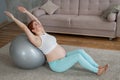 Pregnant red-haired woman doing exercises on fitness ball at home. Royalty Free Stock Photo