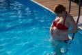 Pregnant red-haired woman in the pool in a red bikini. Royalty Free Stock Photo