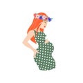 Pregnant red-heared woman wearing floral wreath and polka-dot dress. Royalty Free Stock Photo