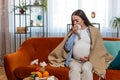 Pregnant sick ill unhealthy woman wrapped in blanket blowing nose suffering from flu cold symptoms Royalty Free Stock Photo