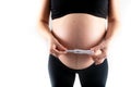 Pregnant skinny slim fit woman holding a positive pregnancy test on her belly tummy abdomen