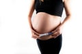 Pregnant skinny slim fit woman holding a positive pregnancy test on her belly tummy abdomen