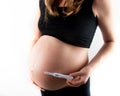 Pregnant skinny slim fit woman holding a positive pregnancy test on her belly tummy abdomen