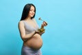 Pregnant slim woman with big belly eats vegetable salad isolated over blue wall Royalty Free Stock Photo
