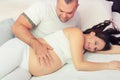 Pregnant smiling woman and her husband lying in bed touching Royalty Free Stock Photo